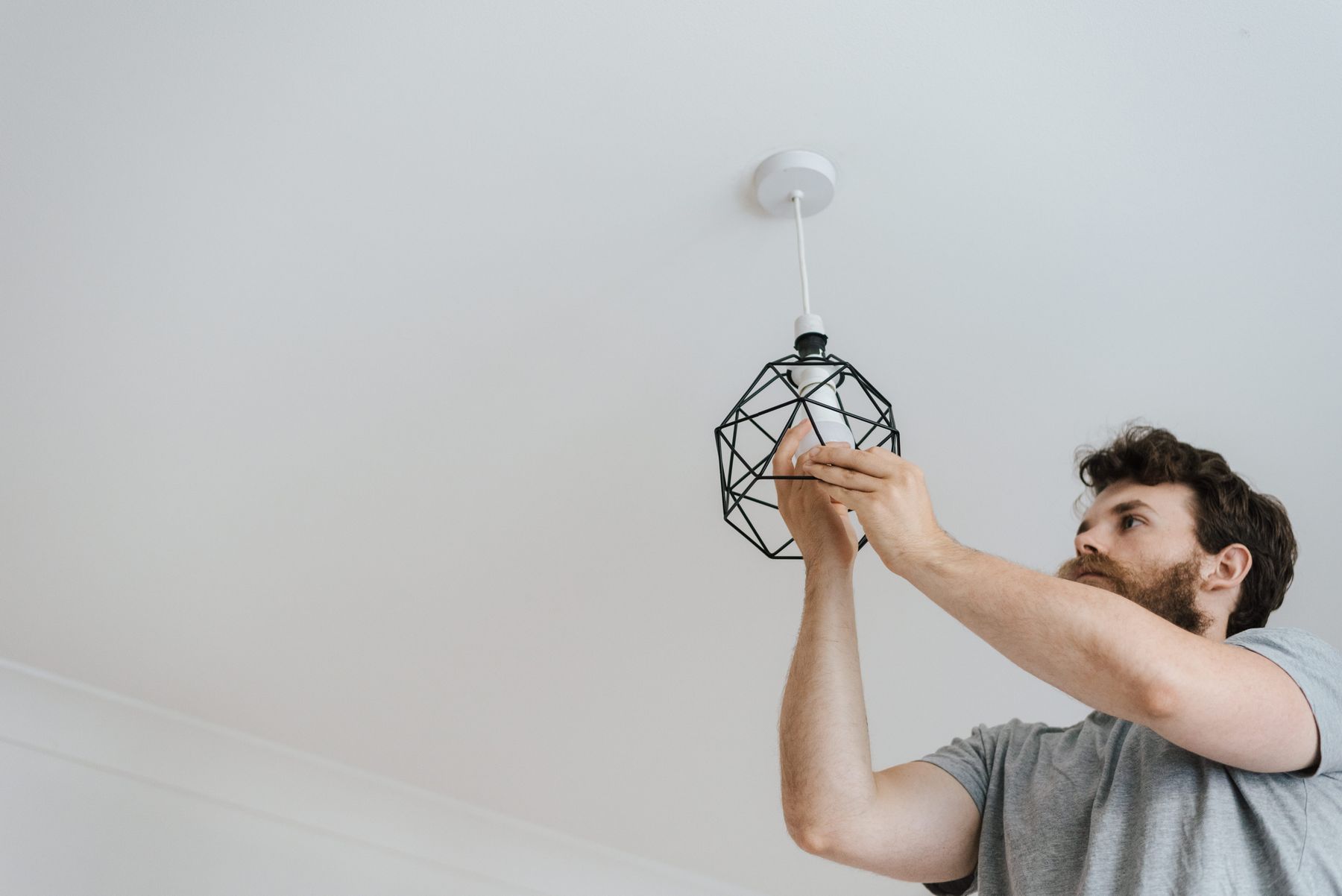 Worker installing a light bulb in a ceiling fixture